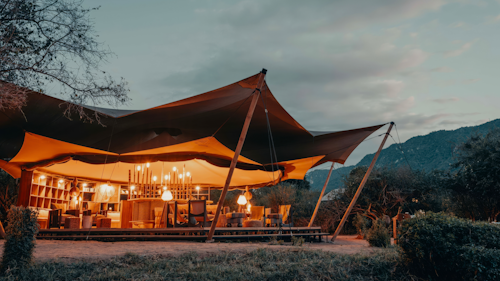 Located on the banks of the Endabash River in the south of the park, at the bottom of a huge waterfall, the setting provides beautiful views of the park down to Lake Manyara. The pools in the rocks below the waterfall provide the perfect reprieve for a safe swim on hot African afternoons. Manyara Camp comprises eight square en-suite eco-tents on raised platforms. Each tent can be set up as a double, twin, or triple for families. Adjoining tents with an enclosed walkway are ideal for families with older children. Simple luxuries, comfortable beds, crisp linen, low flush toilets and classic bush showers ensure complete relaxation after a full day enjoying the wildlife. The stylish central mess tent has lounge chairs and a small library. All Wayo Green Camps operate in the most environmentally sustainable manner and are 100% plastic-free, using solar-powered lighting and recycling all applicable materials.

INSIDER’S TIP: For some parts of the year, the Endabash River is the only source of water for miles, attracting thousands of animals – including elephants and buffalos – creating breathtaking scenes.