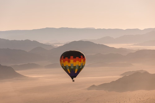 Take to the skies on a spectacular balloon flight over mesmerising Sossusvlei in the Namib Sand Sea, one of the oldest deserts on earth. As the sun rises, you'll lift off and drift gracefully over the endless vistas of towering dunes and mountains, capturing the desert's ancient beauty from a unique perspective. 

Experience the magic of the desert for approximately one hour, with the shifting shadows and lights creating an unforgettable spectacle below. Upon landing, indulge in an "Out of Africa" - style champagne breakfast set in the heart of the desert. Enjoy a decadent feast and exchange stories with your pilot in these stunning surroundings.

After breakfast, a scenic nature drive will take you back to your starting point, allowing you to soak in the splendour of Sossusvlei one last time. This enchanting adventure promises memories that will last a lifetime, leaving you floating on air long after your flight is over.