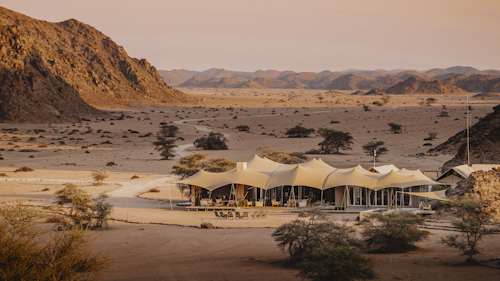 The name “Skeleton Coast” conjures up romantic images of desolate beauty, and the proudly remote Wilderness Hoanib Skeleton Coast Camp in the Kaokoveld does not disappoint. The dry bed of the Hoanib River supports a thin green ribbon of vegetation and the wild beaches of the Atlantic coast are within reach, with their noisy seal colonies and eerily quiet shipwreck remnants.

Eight large en-suite tents (including one family unit) and the main area provide shady viewpoints, while nature drives into the surrounding area reveal a wealth of desert-adapted wildlife. Desert-adapted lion and brown hyena may also be glimpsed in this vast but far from lifeless landscape. 

Insider's Tip: On a stay of three nights or more, a coastal excursion to The Skeleton Coast is included. Usually involving a drive down to the coast and a flight back to camp, to see such a diverse area both on the ground and in the air.
